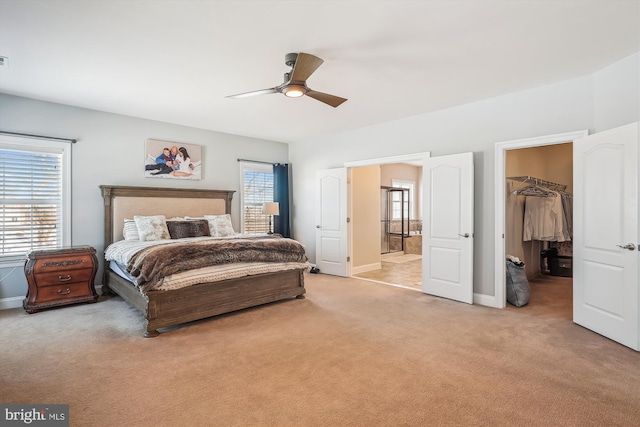 bedroom featuring light colored carpet, ceiling fan, a spacious closet, and a closet