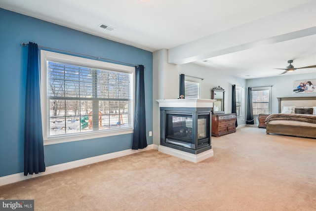 carpeted living room featuring ceiling fan and a multi sided fireplace