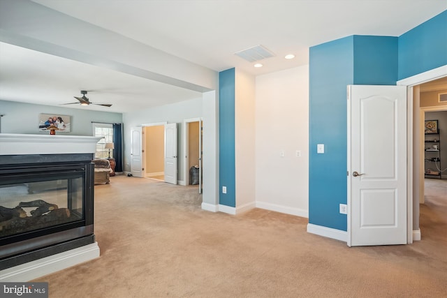 living room with a multi sided fireplace, light carpet, and ceiling fan