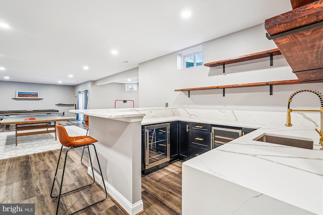 kitchen featuring sink, light stone countertops, a breakfast bar area, and wine cooler