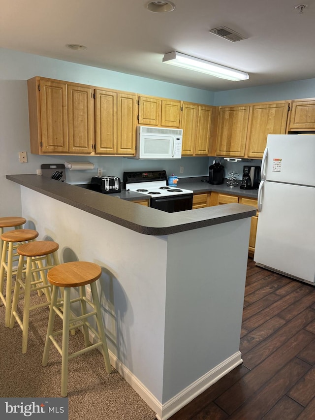 kitchen with a kitchen bar, kitchen peninsula, dark hardwood / wood-style floors, and white appliances