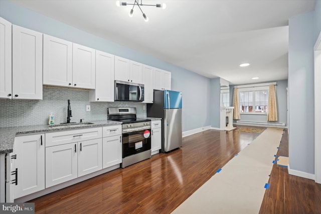 kitchen with light stone countertops, appliances with stainless steel finishes, white cabinetry, and sink