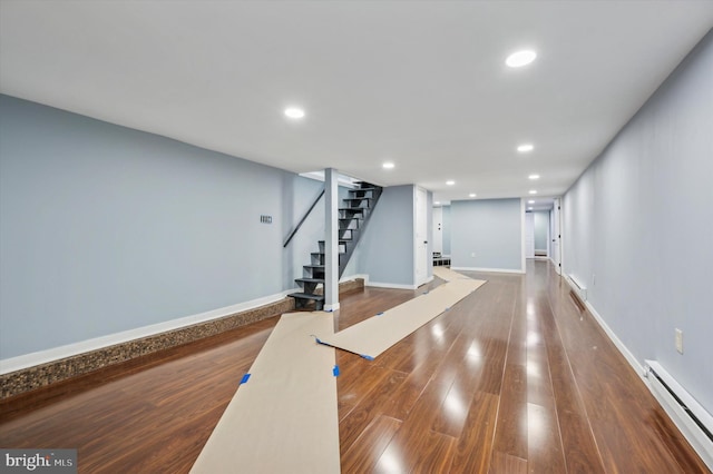 exercise room with baseboard heating and dark wood-type flooring