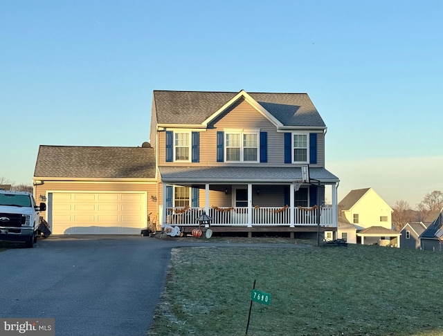 view of front facade featuring a garage, covered porch, and a yard