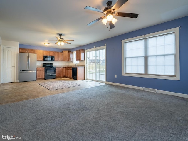 kitchen with ceiling fan, black appliances, light carpet, and sink