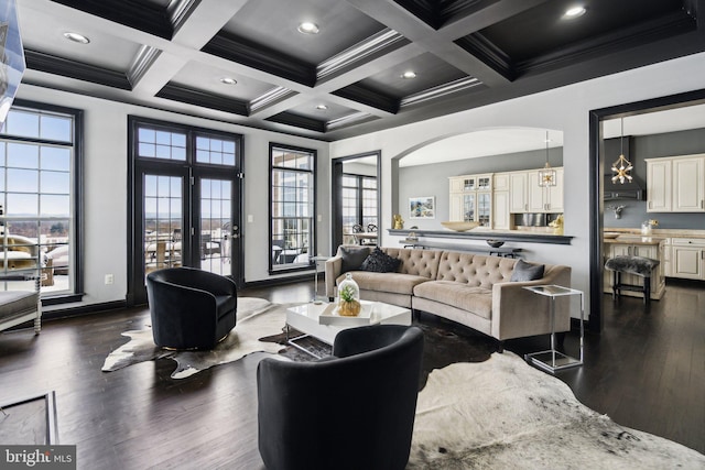 living room with beam ceiling, ornamental molding, coffered ceiling, and a notable chandelier