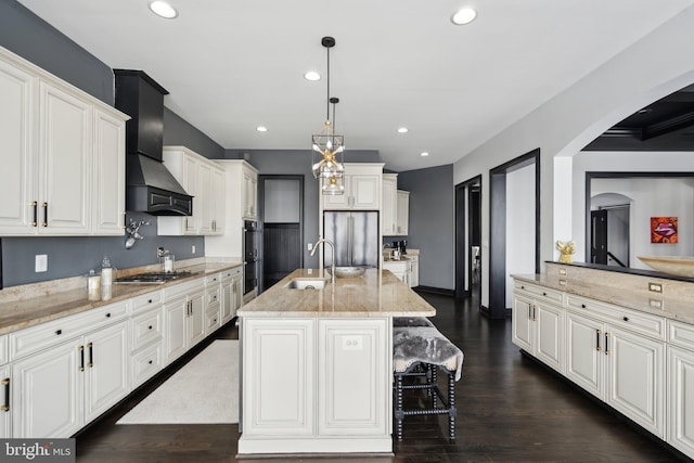 kitchen featuring sink, an island with sink, decorative light fixtures, a breakfast bar, and appliances with stainless steel finishes