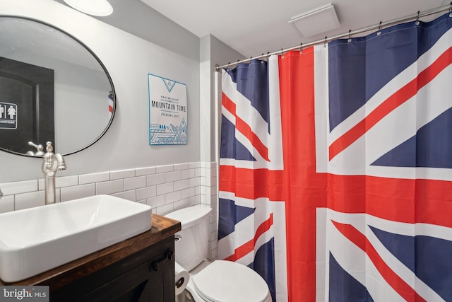 bathroom featuring sink, tile walls, and toilet