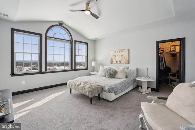 carpeted bedroom with ceiling fan, vaulted ceiling, a walk in closet, and a closet