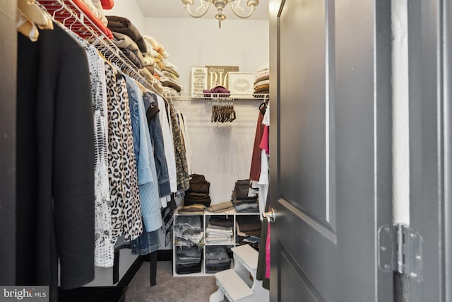 spacious closet with carpet flooring and a notable chandelier