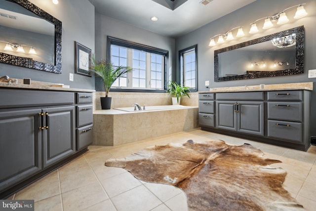 bathroom with tile patterned flooring, a relaxing tiled tub, and vanity