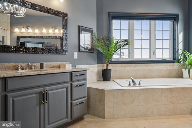 bathroom featuring tile patterned floors, a relaxing tiled tub, and vanity