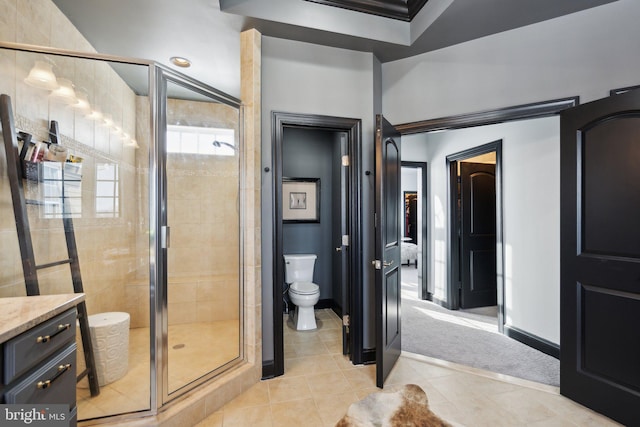 bathroom featuring tile patterned flooring, vanity, a shower with shower door, and toilet