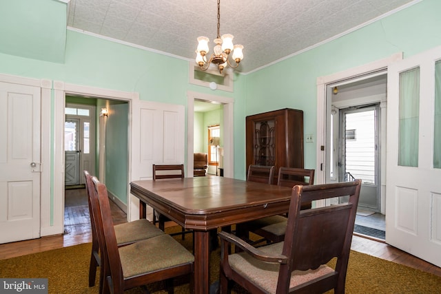 dining space with a notable chandelier, dark hardwood / wood-style floors, and ornamental molding