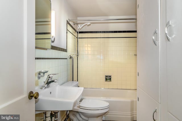 full bathroom with tile walls, sink, tiled shower / bath combo, and toilet