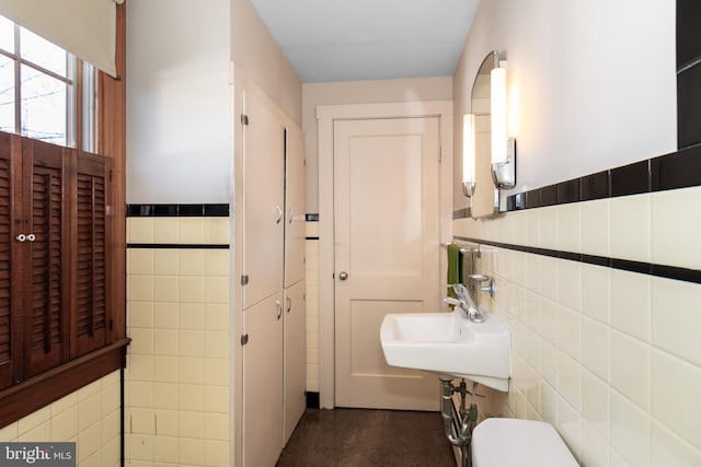 bathroom featuring sink, tile walls, and toilet