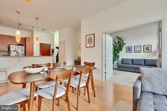 dining room with light hardwood / wood-style floors and track lighting