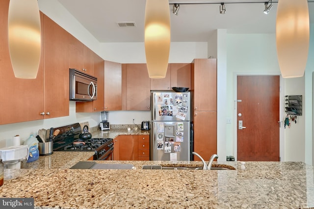 kitchen with light stone counters, kitchen peninsula, sink, and appliances with stainless steel finishes