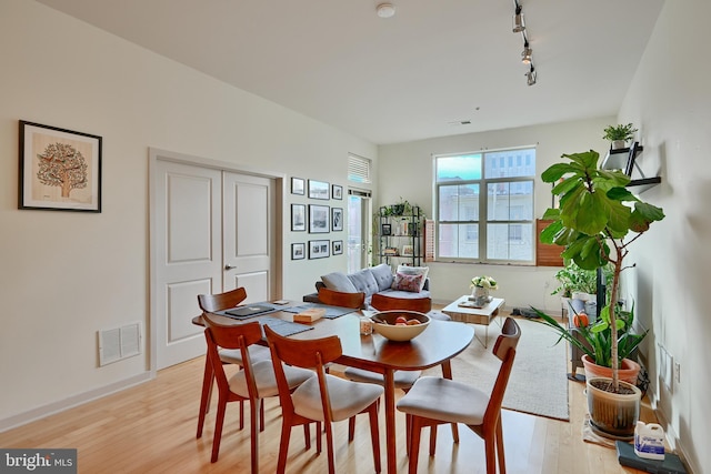 dining space with light hardwood / wood-style flooring and track lighting