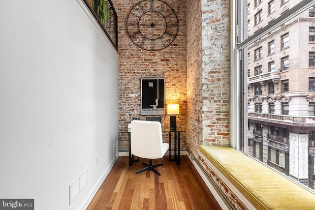 home office featuring baseboards, a high ceiling, visible vents, and wood finished floors