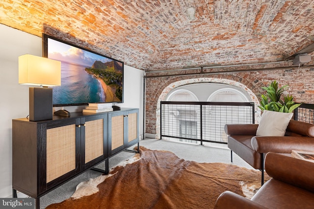 sitting room with brick ceiling, carpet, and brick wall