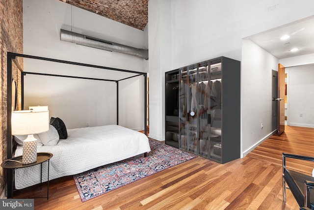 bedroom featuring a high ceiling, wood finished floors, and baseboards