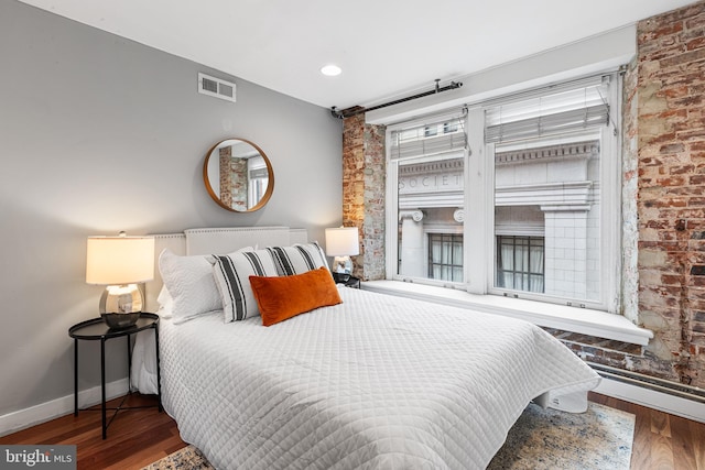 bedroom with baseboards, visible vents, and wood finished floors