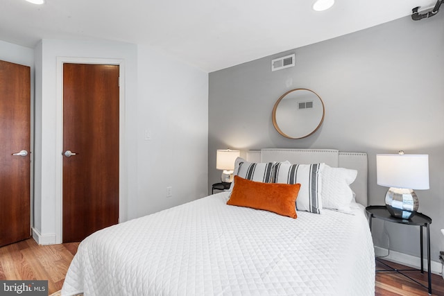 bedroom with baseboards, visible vents, and wood finished floors