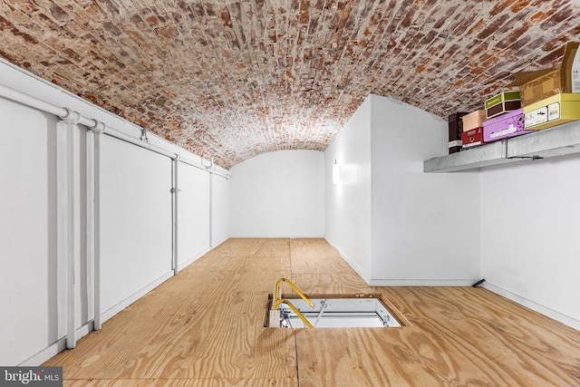 hall featuring brick ceiling, vaulted ceiling, wood finished floors, and baseboards