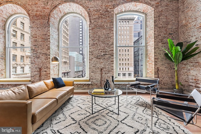 living room featuring brick wall, a high ceiling, and wood finished floors