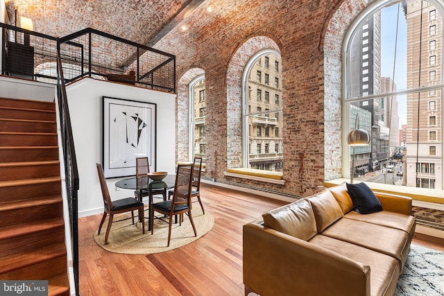 dining space with brick ceiling, a high ceiling, stairway, and wood finished floors