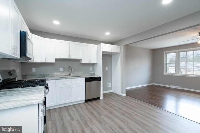 kitchen featuring white cabinets, stainless steel dishwasher, sink, white range with gas stovetop, and light hardwood / wood-style floors