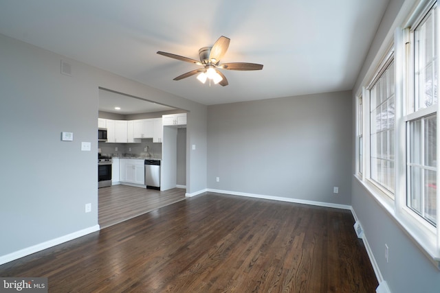 unfurnished living room with ceiling fan, sink, and dark wood-type flooring