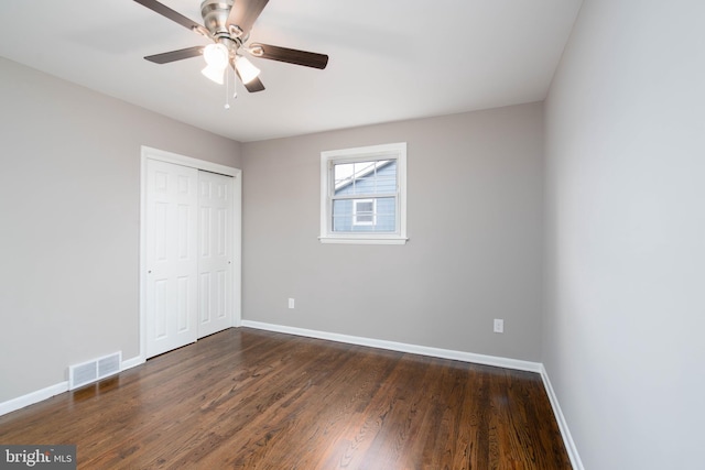 unfurnished bedroom with dark hardwood / wood-style flooring, a closet, and ceiling fan