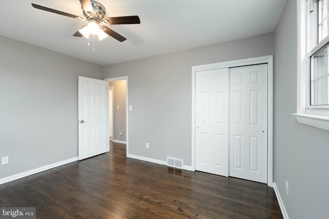 unfurnished bedroom featuring ceiling fan, dark hardwood / wood-style flooring, and a closet