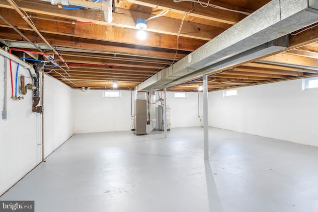 basement with heating unit, a healthy amount of sunlight, and gas water heater