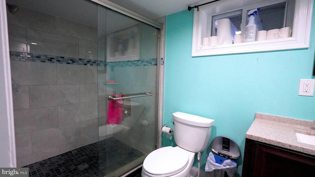 bathroom featuring vanity, toilet, and a shower with shower door