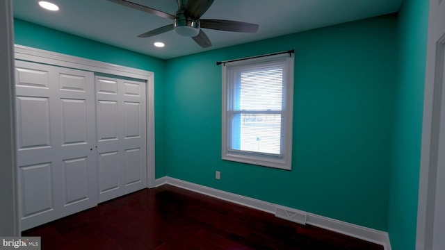 unfurnished bedroom with multiple windows, a closet, ceiling fan, and dark hardwood / wood-style floors