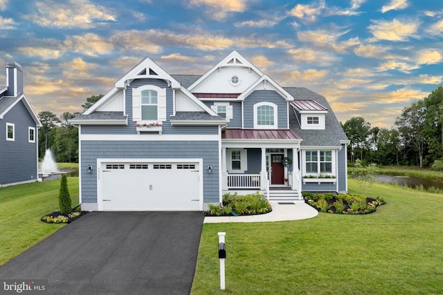 view of front of home with a porch, a standing seam roof, a front lawn, and aphalt driveway