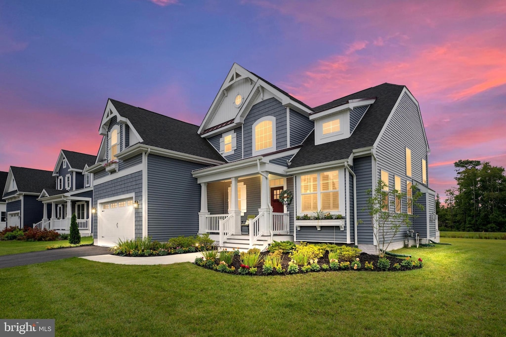 traditional home featuring a lawn, aphalt driveway, roof with shingles, an attached garage, and a porch