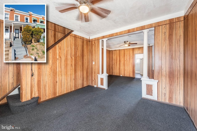 unfurnished room featuring carpet flooring, a textured ceiling, ceiling fan, and wood walls