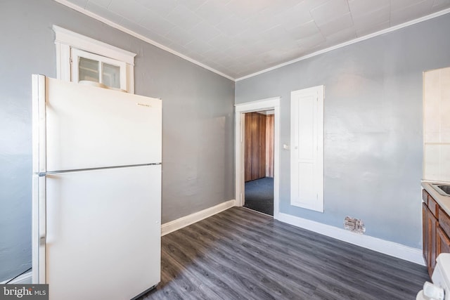 kitchen with crown molding, white fridge, and dark wood-type flooring