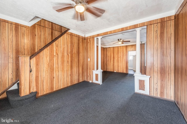 carpeted empty room featuring ceiling fan, a textured ceiling, and wooden walls