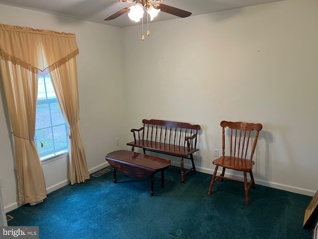 living area featuring dark colored carpet and ceiling fan