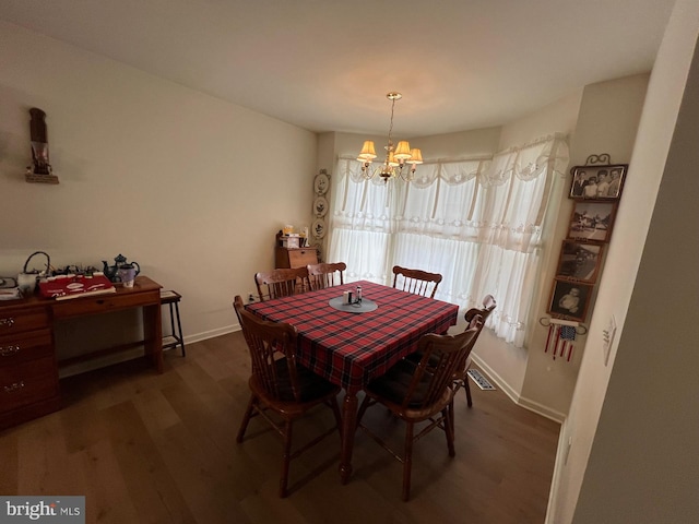 dining room with dark wood-type flooring and a chandelier