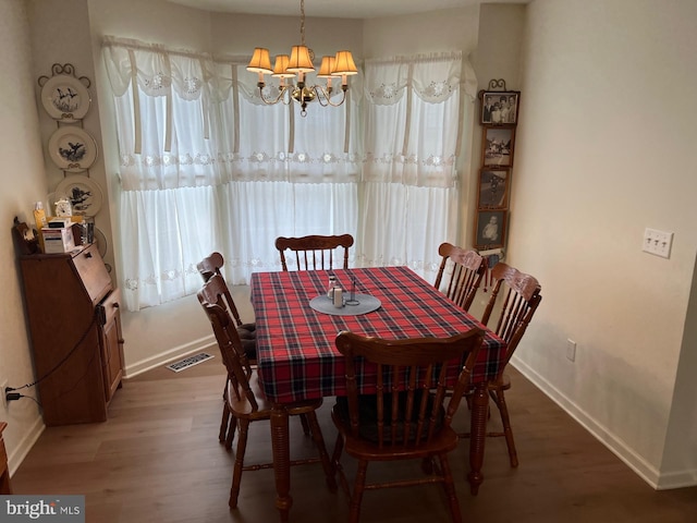 dining area featuring dark wood-type flooring and a notable chandelier