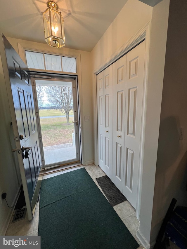 entryway with an inviting chandelier and light tile patterned floors