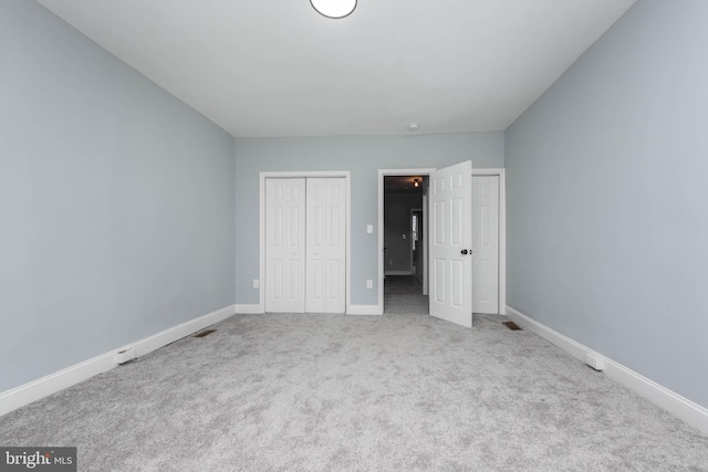 unfurnished bedroom with light colored carpet and a closet