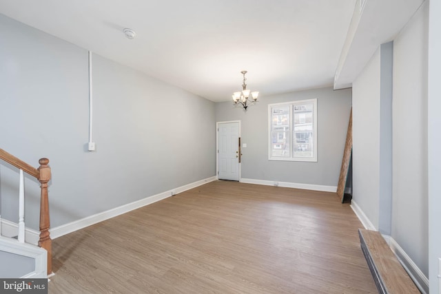 unfurnished room with a chandelier and light hardwood / wood-style flooring