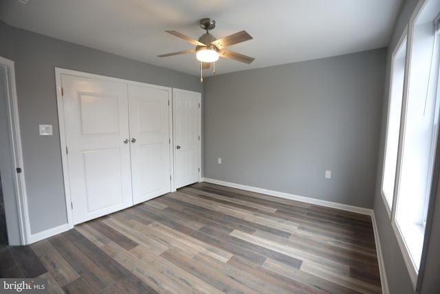 unfurnished bedroom featuring ceiling fan, a closet, and dark wood-type flooring